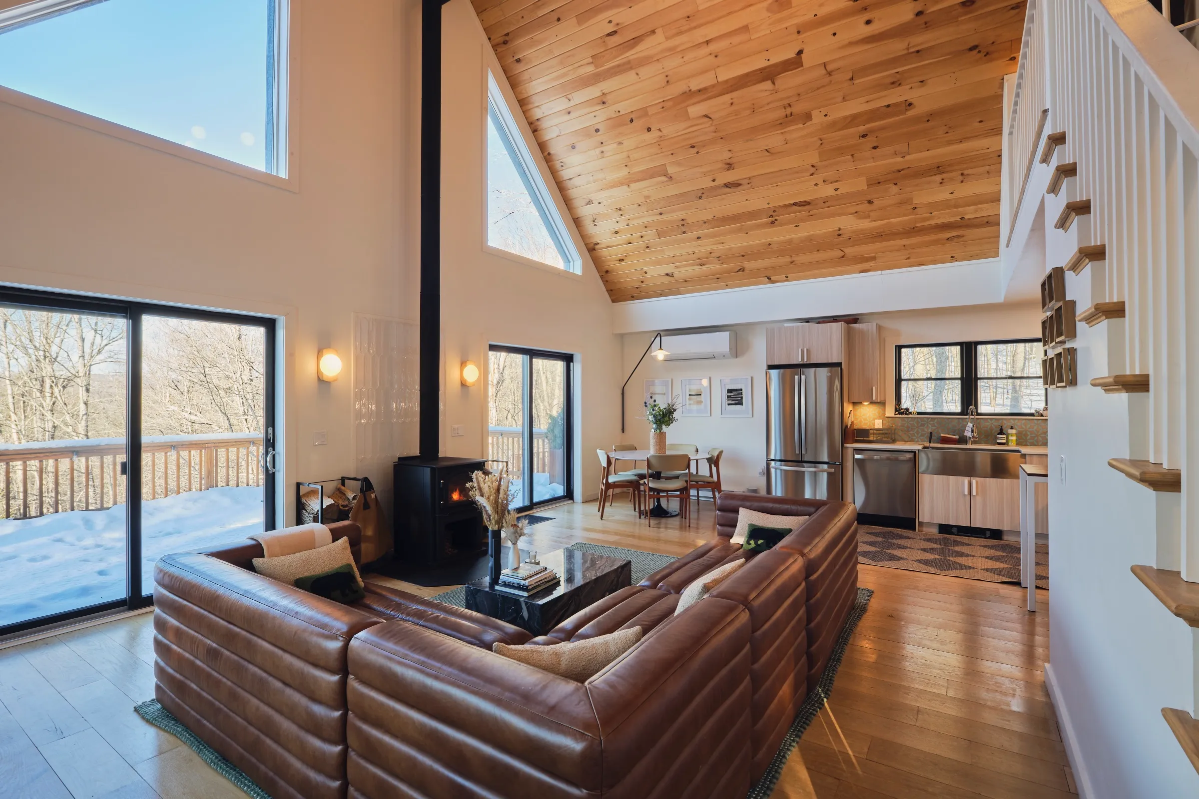 The cathedral-ceiling great room with leather sofas and a wood stove